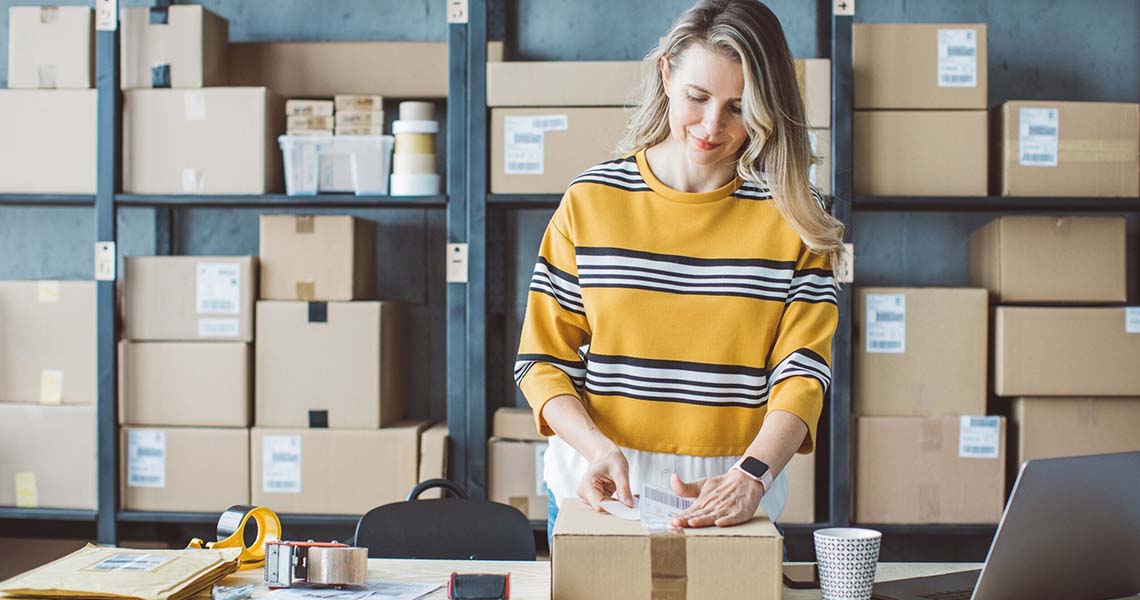 Kvinna som packar paket i lagerlokal