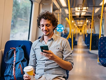 Leende ung man tittar i sin smartphone på tunnelbanan